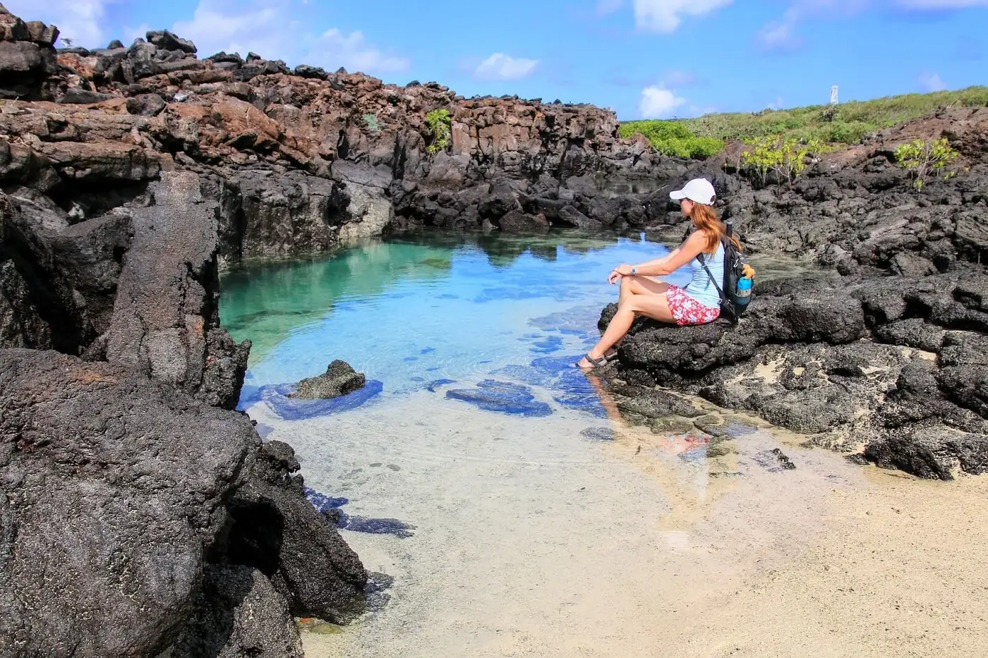 Besucherin an einem Wasserbecken zwischen Lavafelsen auf Galápagos